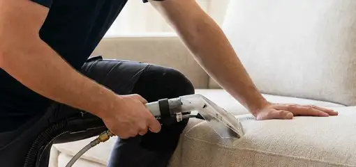 Professional upholstery cleaner deep-cleaning a fabric sofa with a handheld extraction tool, Fort Worth, TX.